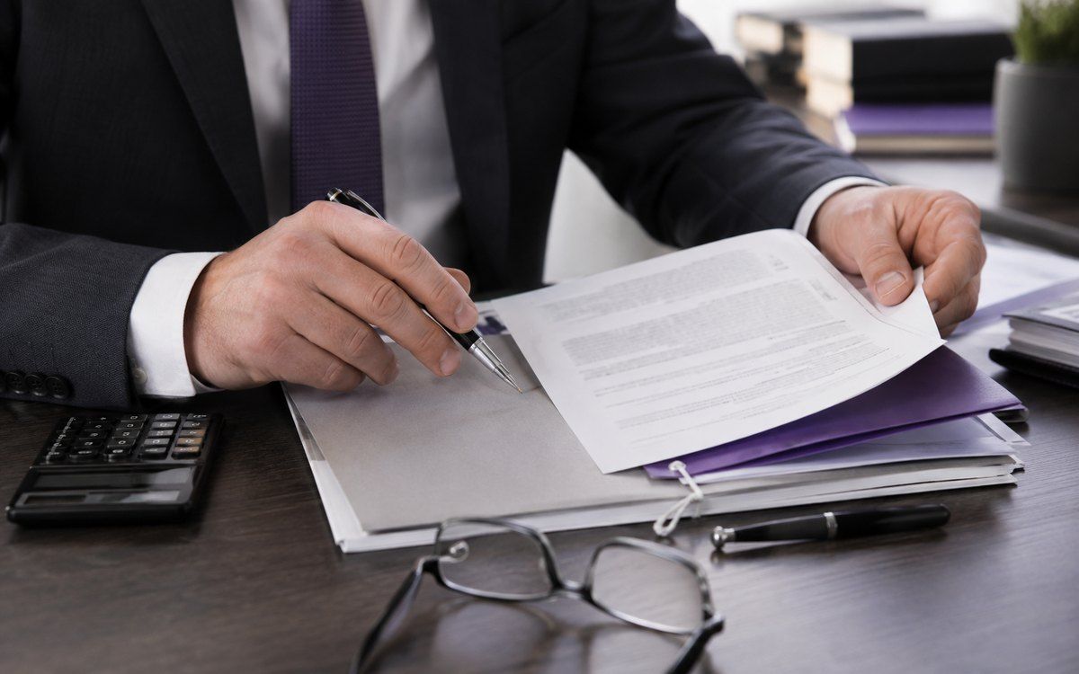 Tax professional reviewing and signing documents in a violet folder